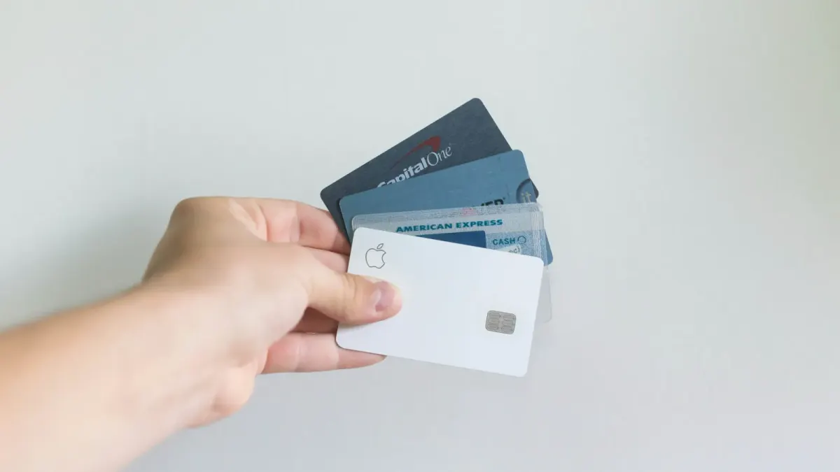 Hand fanning a white Apple Card with other bank cards
