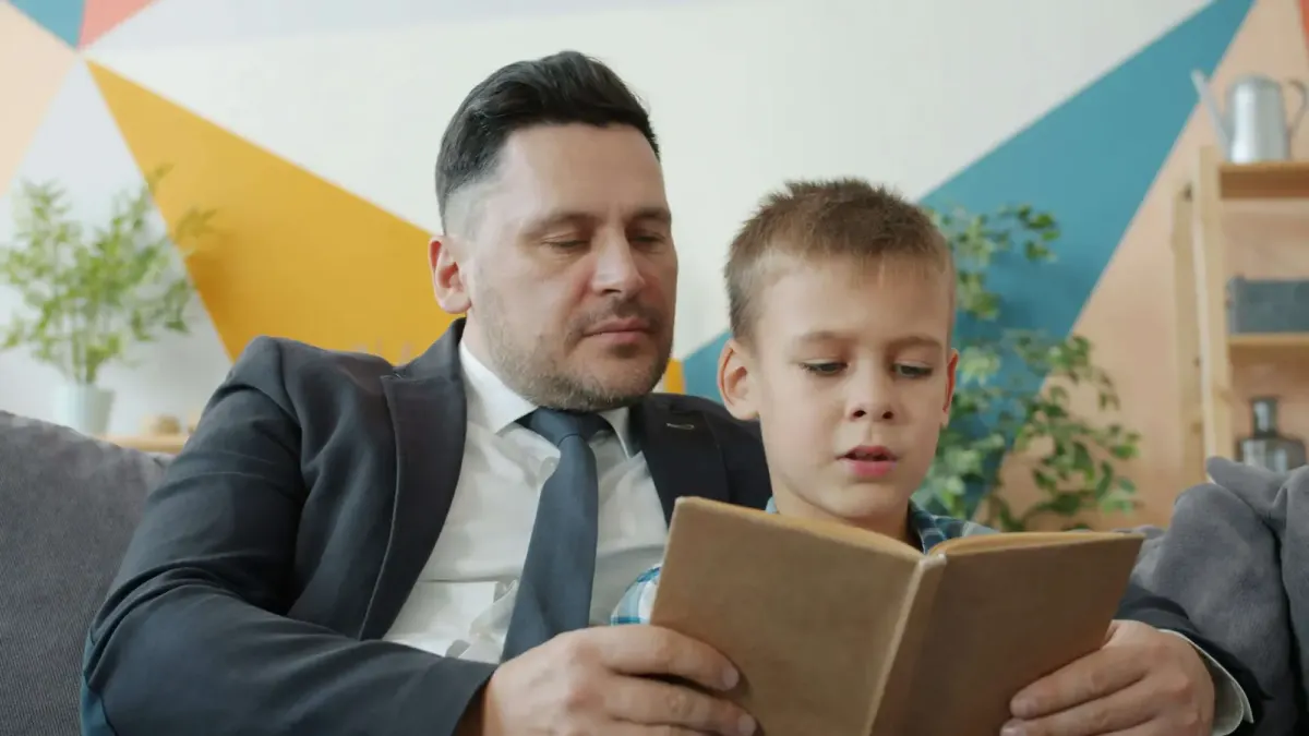 Father in a suit reading a book with his young son