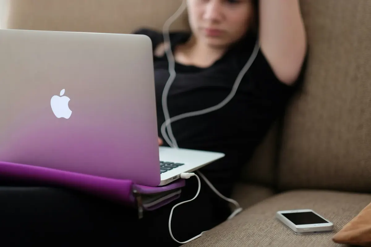Girl using her mac computer in the couch