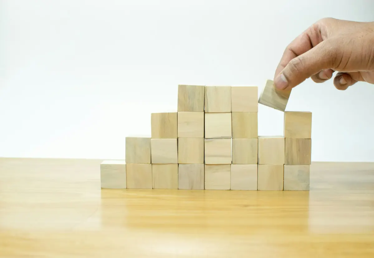 Hand placing a wooden block onto a staircase-shaped block stack