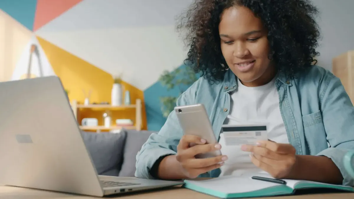 Afroamerican girl holds a debit card and a phone