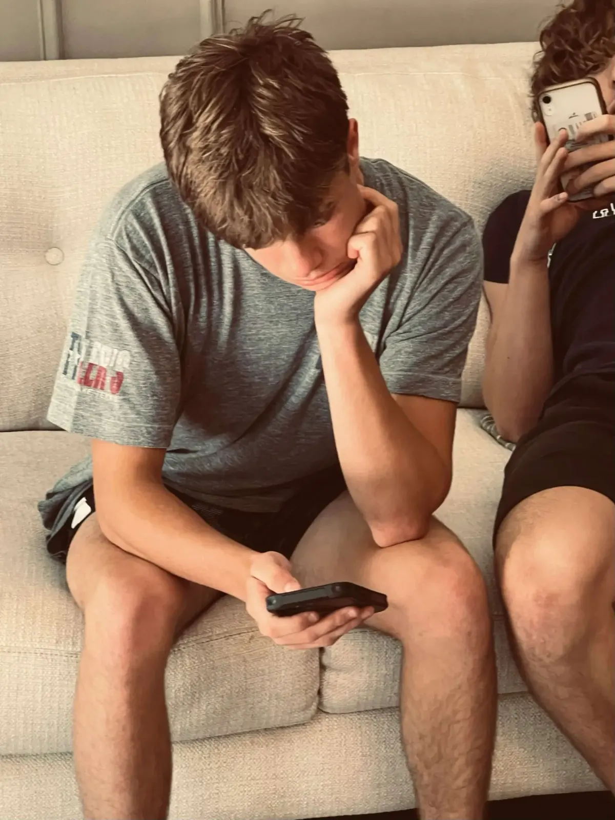 Teen boy sitting on a couch looking down at his phone
