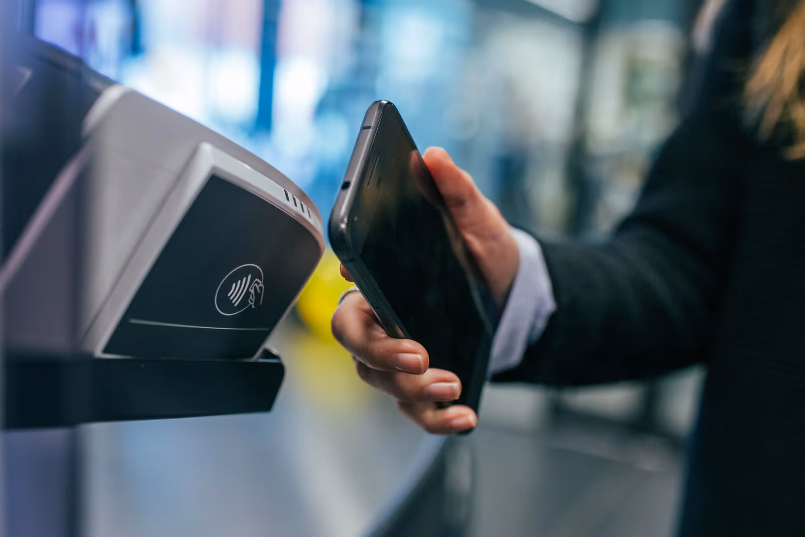 Hand tapping a phone against a contactless payment terminal